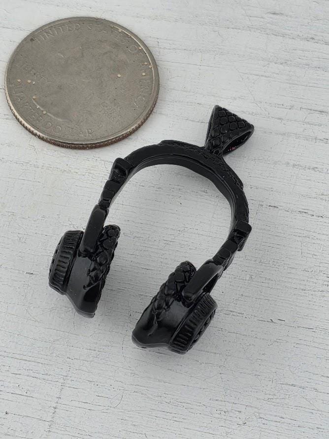 A pair of black headphones is displayed in a white box, with a gold gift box and a red ribbon visible in the background.