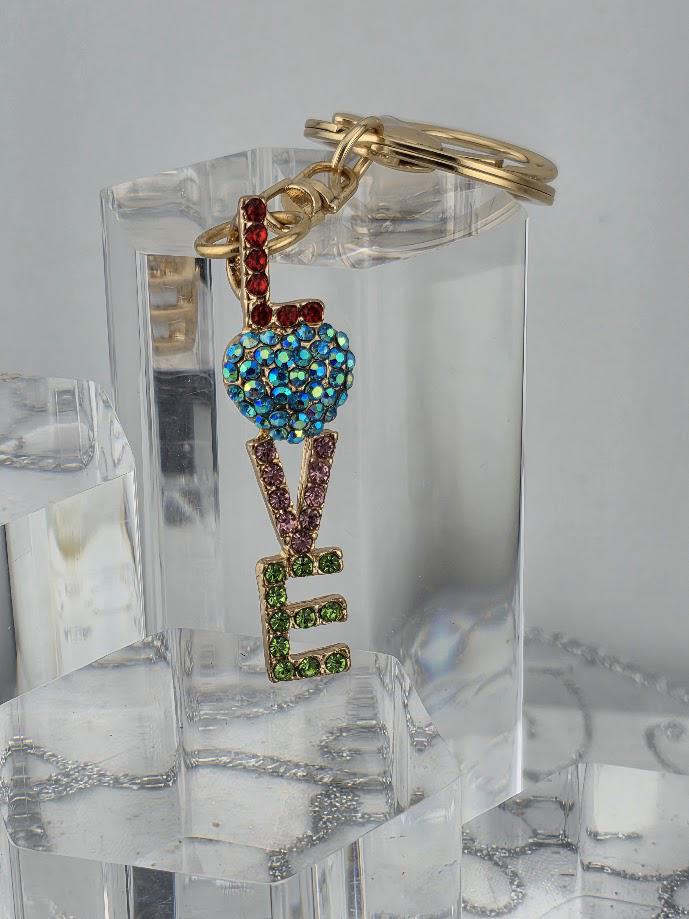 A clear glass keychain with a colorful pendant that says "LOVE" in a stylized font.