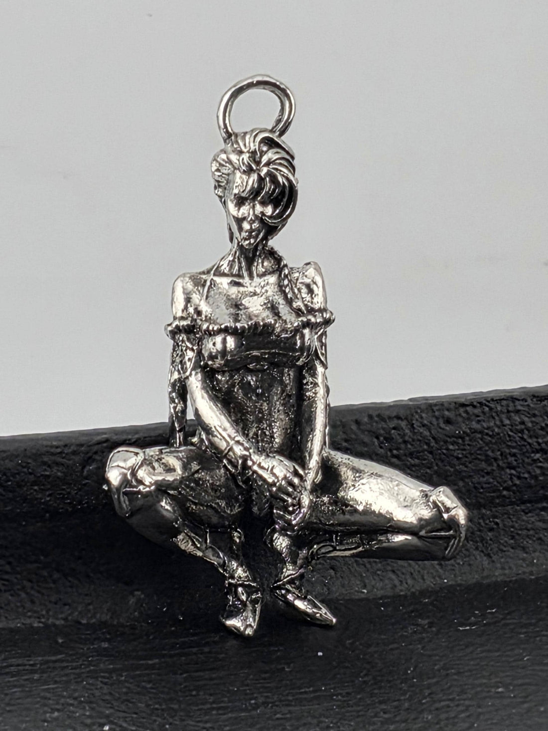 A close-up view of a shiny, metallic object resembling a pendant or charm, with intricate details and a textured surface.