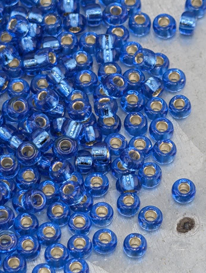 a large pile of blue glass beads scattered on a surface.