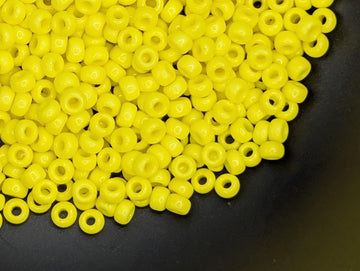 A pile of bright yellow beads on a black surface.