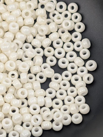 a close-up view of numerous small, white beads scattered on a dark surface.