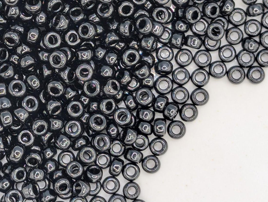 a close-up view of numerous black beads or beads scattered across a white surface.