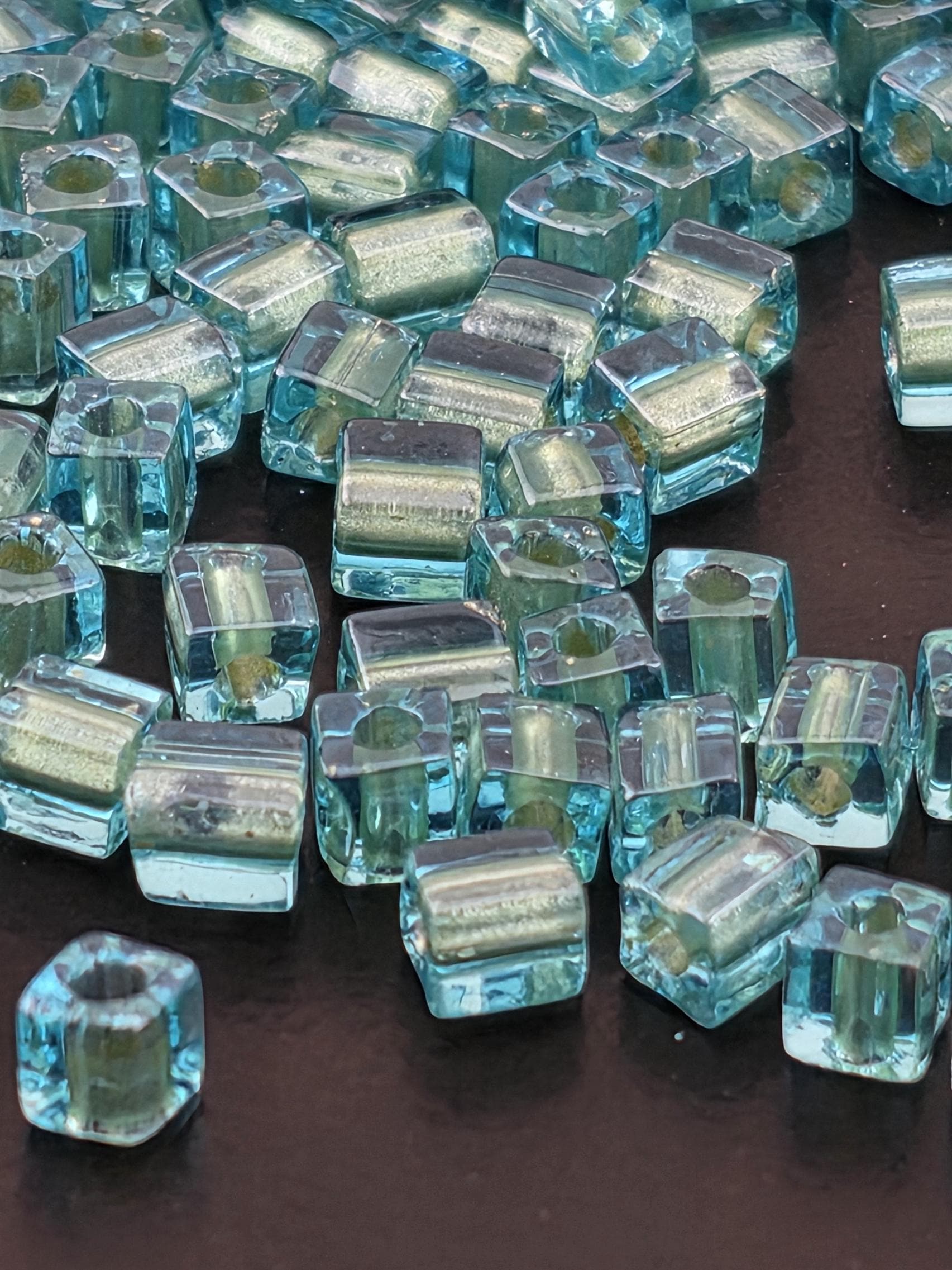 a collection of small, clear glass beads scattered on a dark surface.