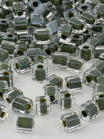 numerous transparent glass beads in various shades of green, scattered across a white background.
