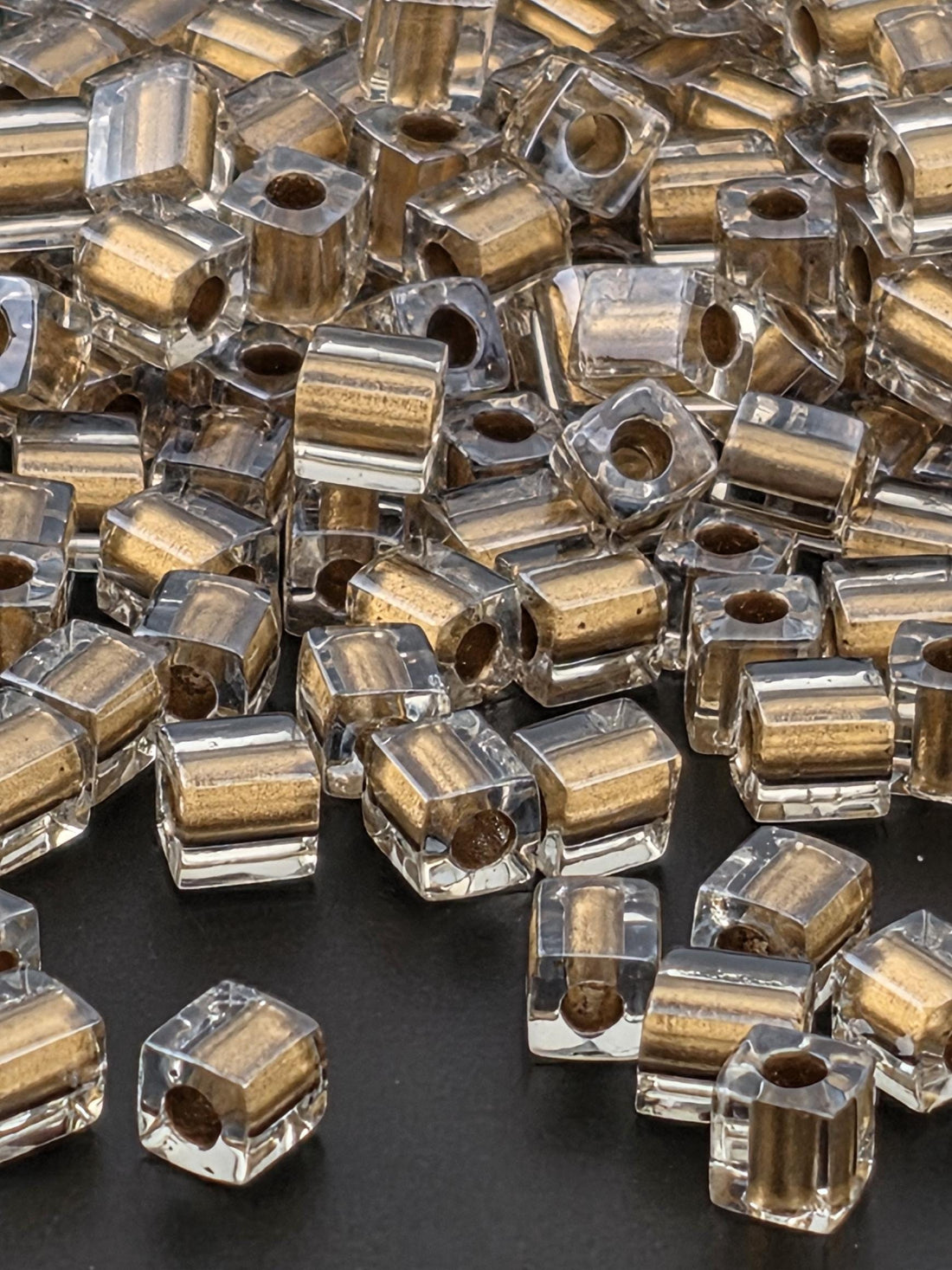 a close-up view of numerous clear glass beads scattered on a dark background.