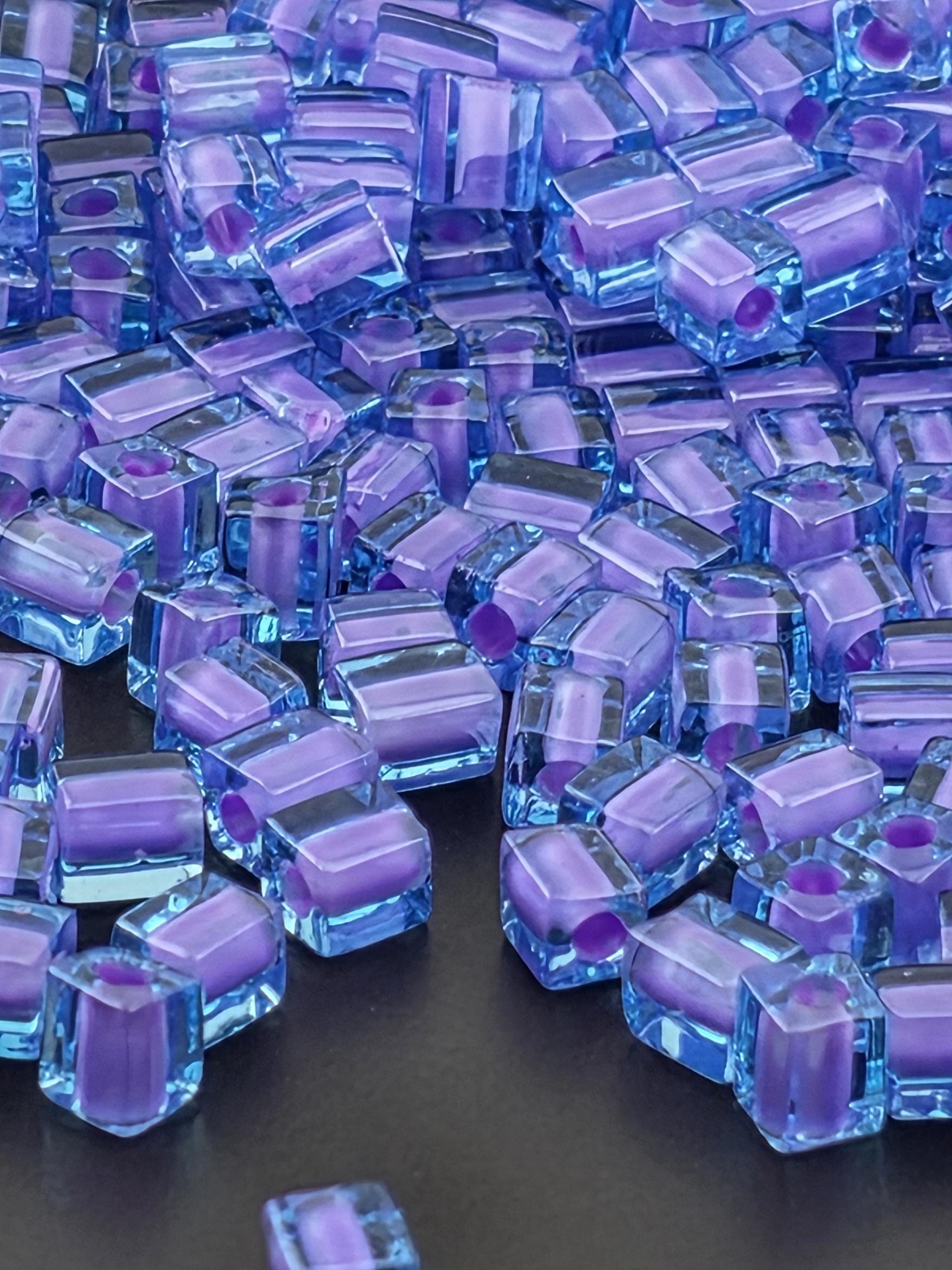 The image is a close-up of numerous small, clear, and purple-colored cubes or blocks arranged in a visually appealing manner.