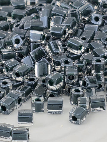 The image is a close-up of numerous small, metallic beads or nuts arranged in a visually striking manner.