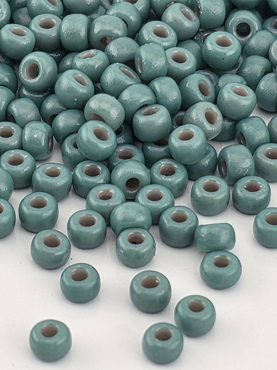 a collection of small, round beads in various shades of blue and green, scattered across a white surface.