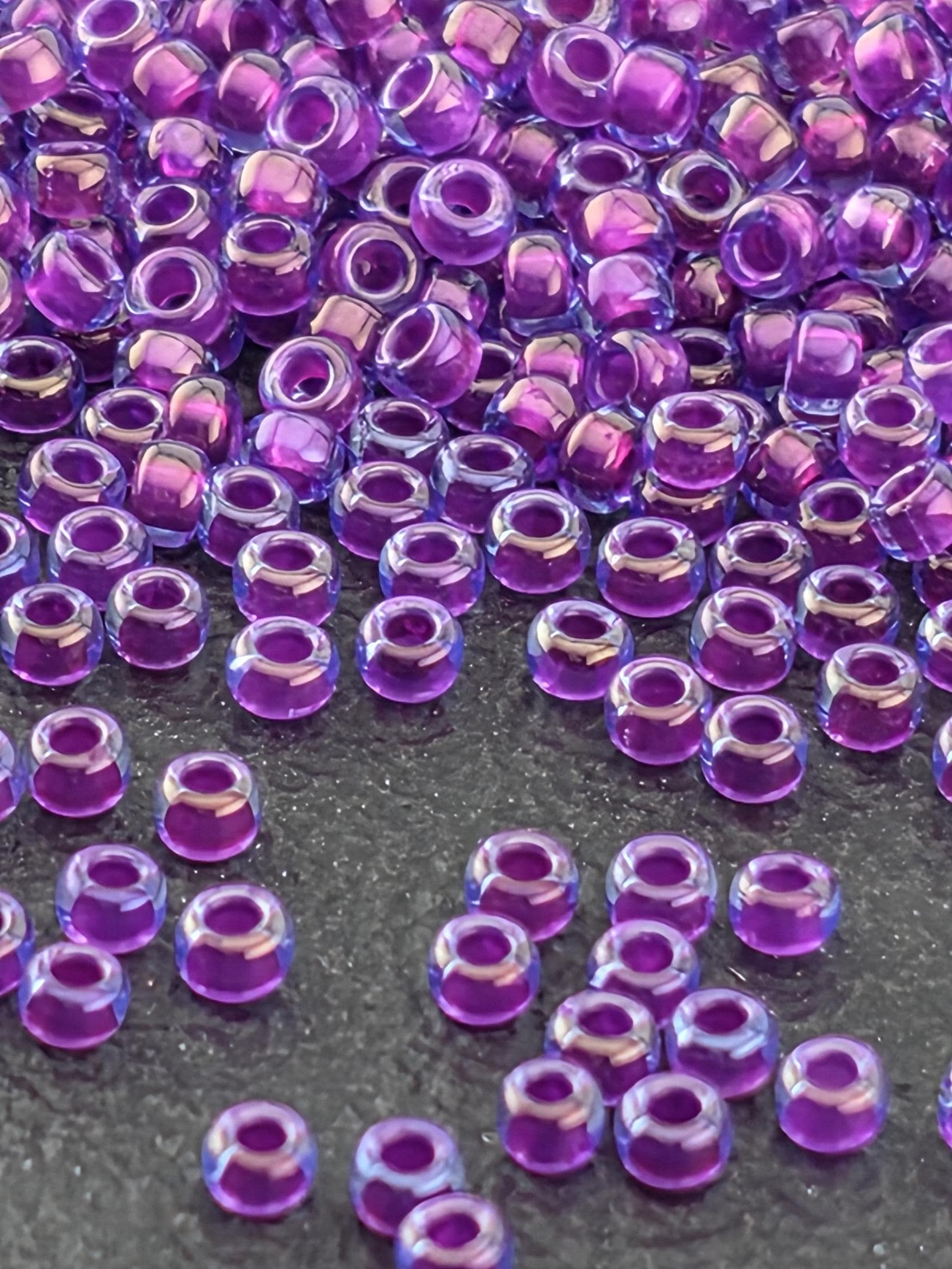 a close-up view of numerous purple and blue beads scattered on a dark surface.