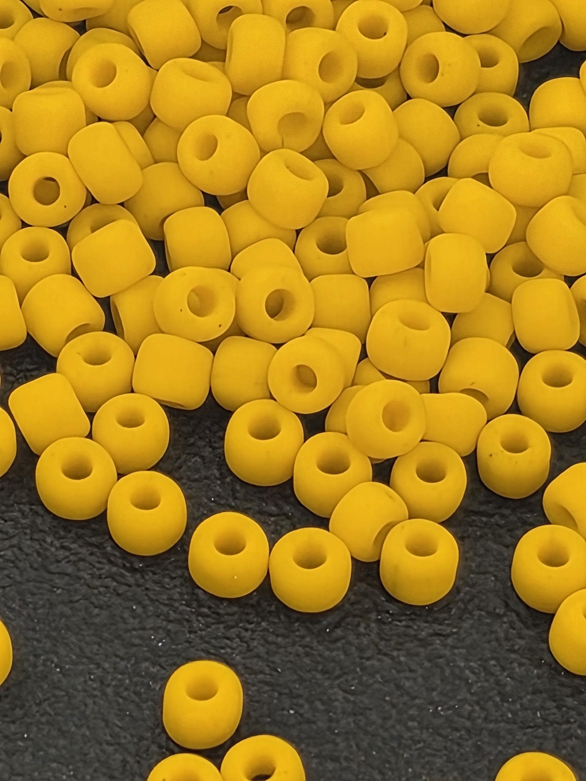 a close-up view of numerous yellow beads scattered on a dark surface.