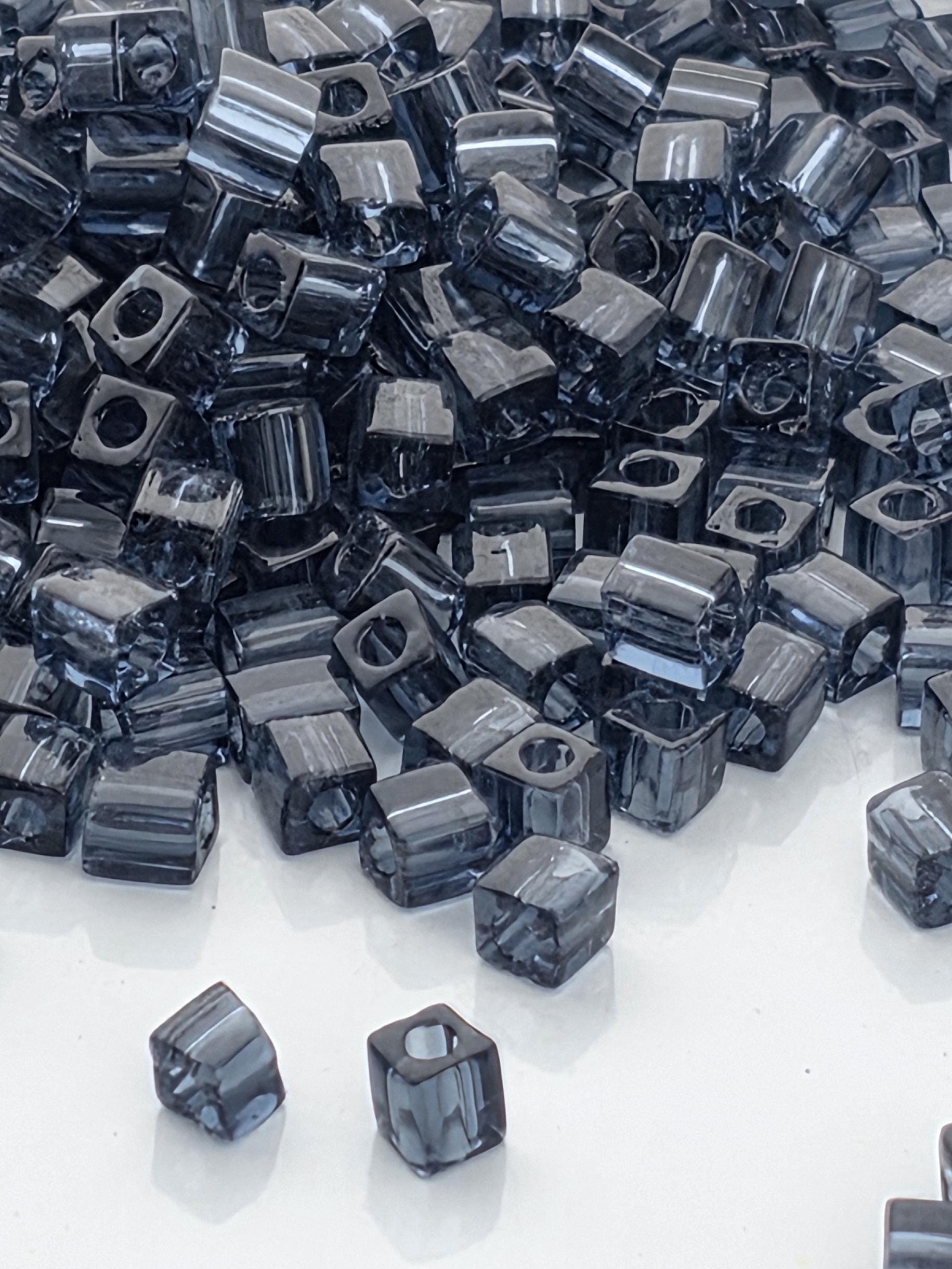 a large pile of small, square-shaped objects, likely made of metal or glass, scattered across a white surface.