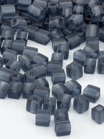 numerous small, square-shaped objects that appear to be made of a dark material, possibly metal or plastic. The objects are scattered across a surface, creating a visually interesting and somewhat chaotic arrangement.