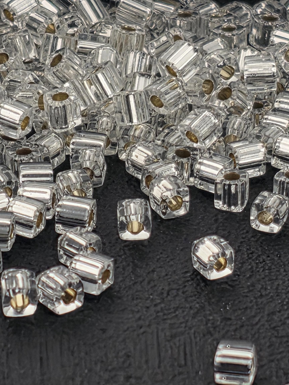 a close-up view of numerous clear glass beads scattered on a black surface.