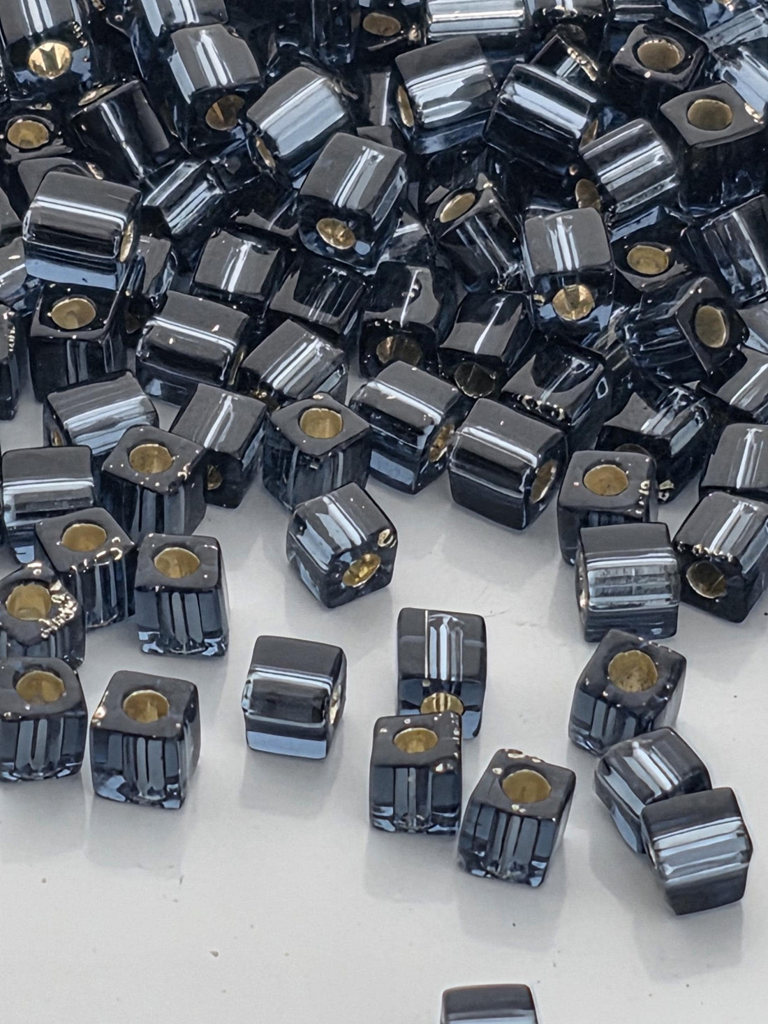 a large pile of black and silver beads scattered on a white surface.