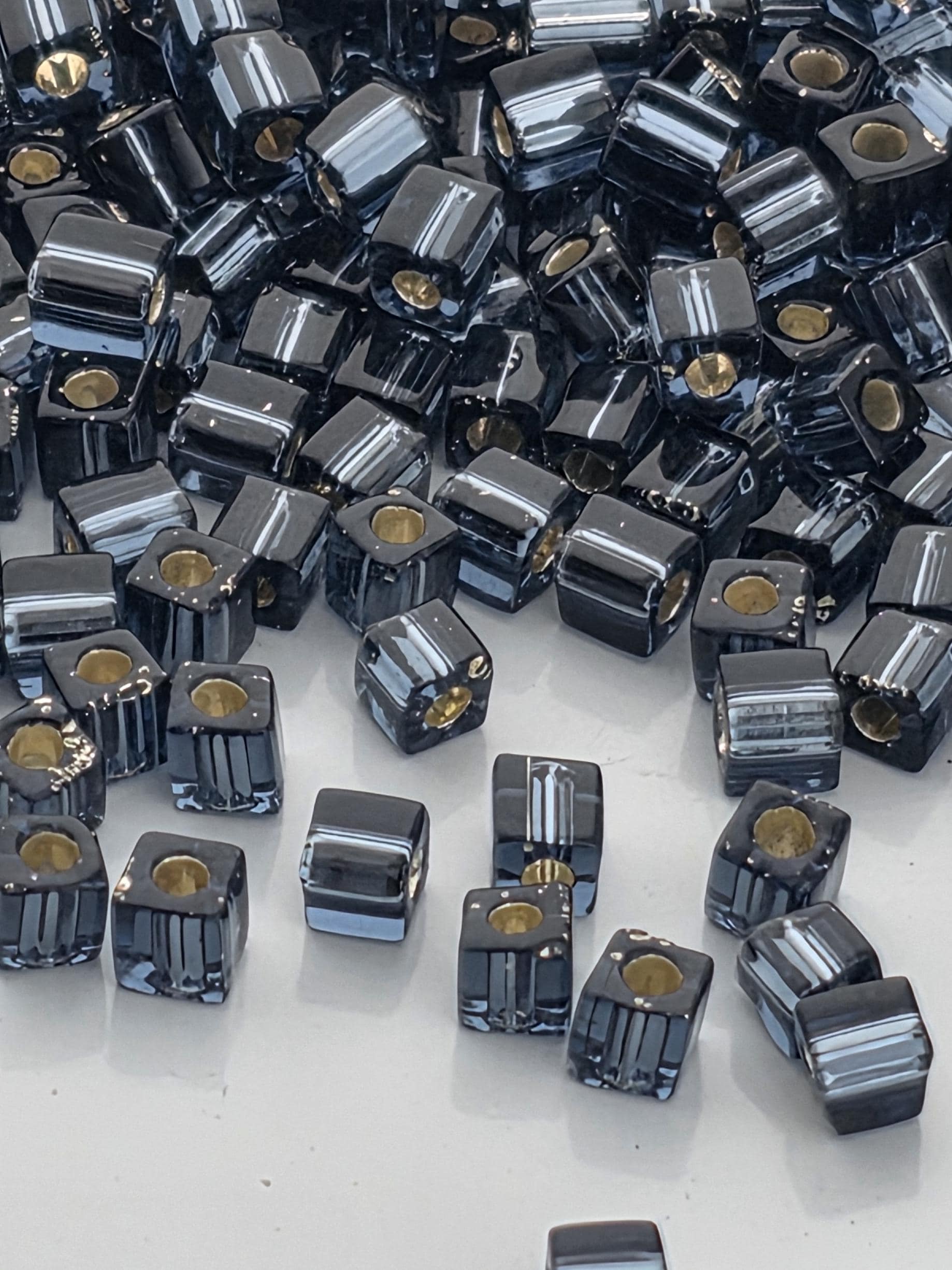 a large pile of black and silver beads scattered on a white surface.