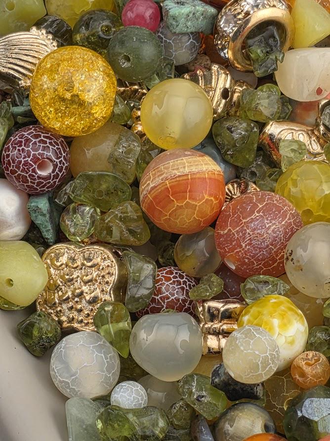 A large collection of colorful beads and gemstones arranged on a white surface.