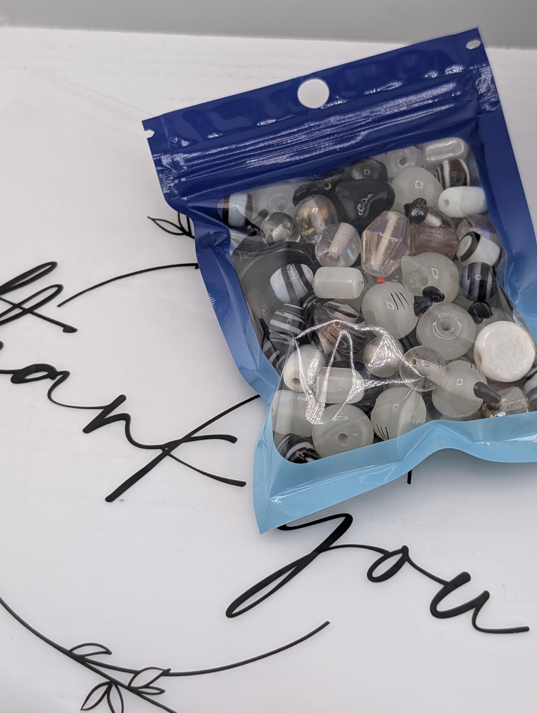 A blue and white bag filled with various beads and charms is placed on a white surface.