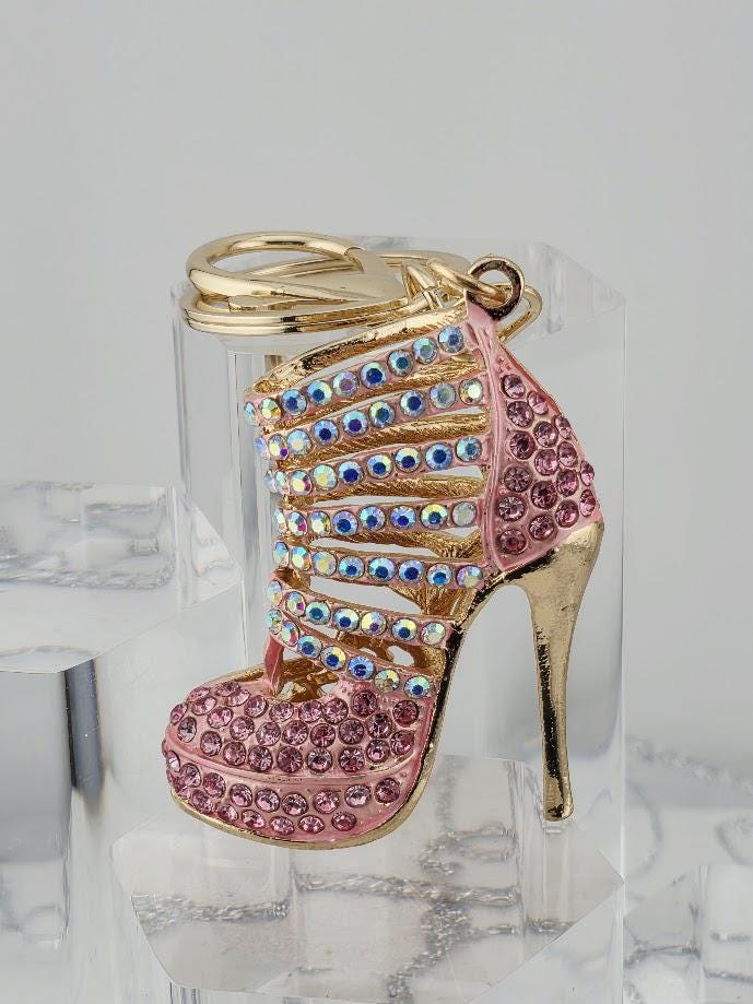 A pink high-heeled shoe keychain with rhinestones and a gold-colored keyring is displayed in a black box.
