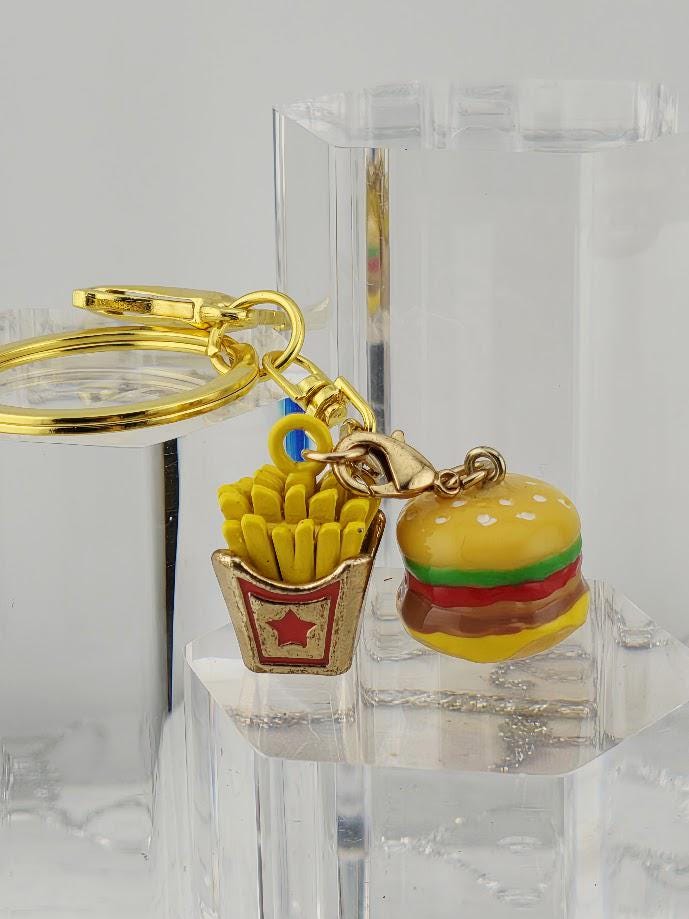 A keychain with a gold-colored metal ring and a small toy hamburger, along with a small red and gold french fry container.