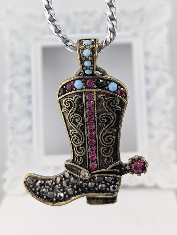 A decorative keychain in the shape of a cowboy boot, adorned with colorful gemstones and a bow.