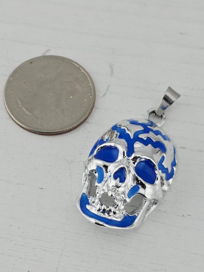 A silver-colored coin is placed next to a blue and silver pendant in the shape of a skull.