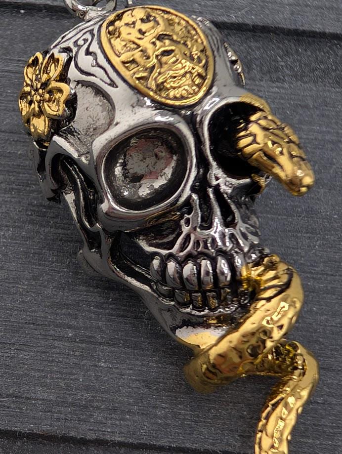A close-up image of a skull pendant with intricate designs and a snake-like element.