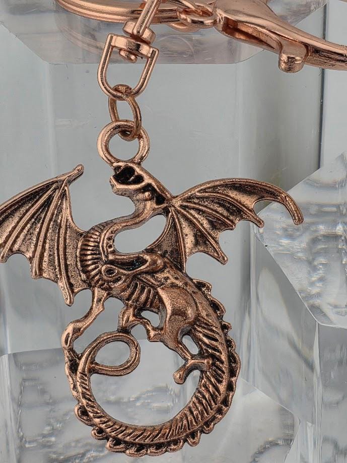A close-up image of a metallic dragon keychain with intricate details and a metallic appearance.