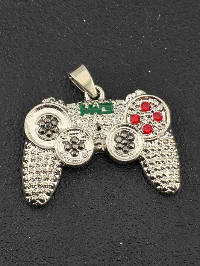 A silver pendant in the shape of a game controller, with red gemstones on the buttons and a green gemstone on the joystick.