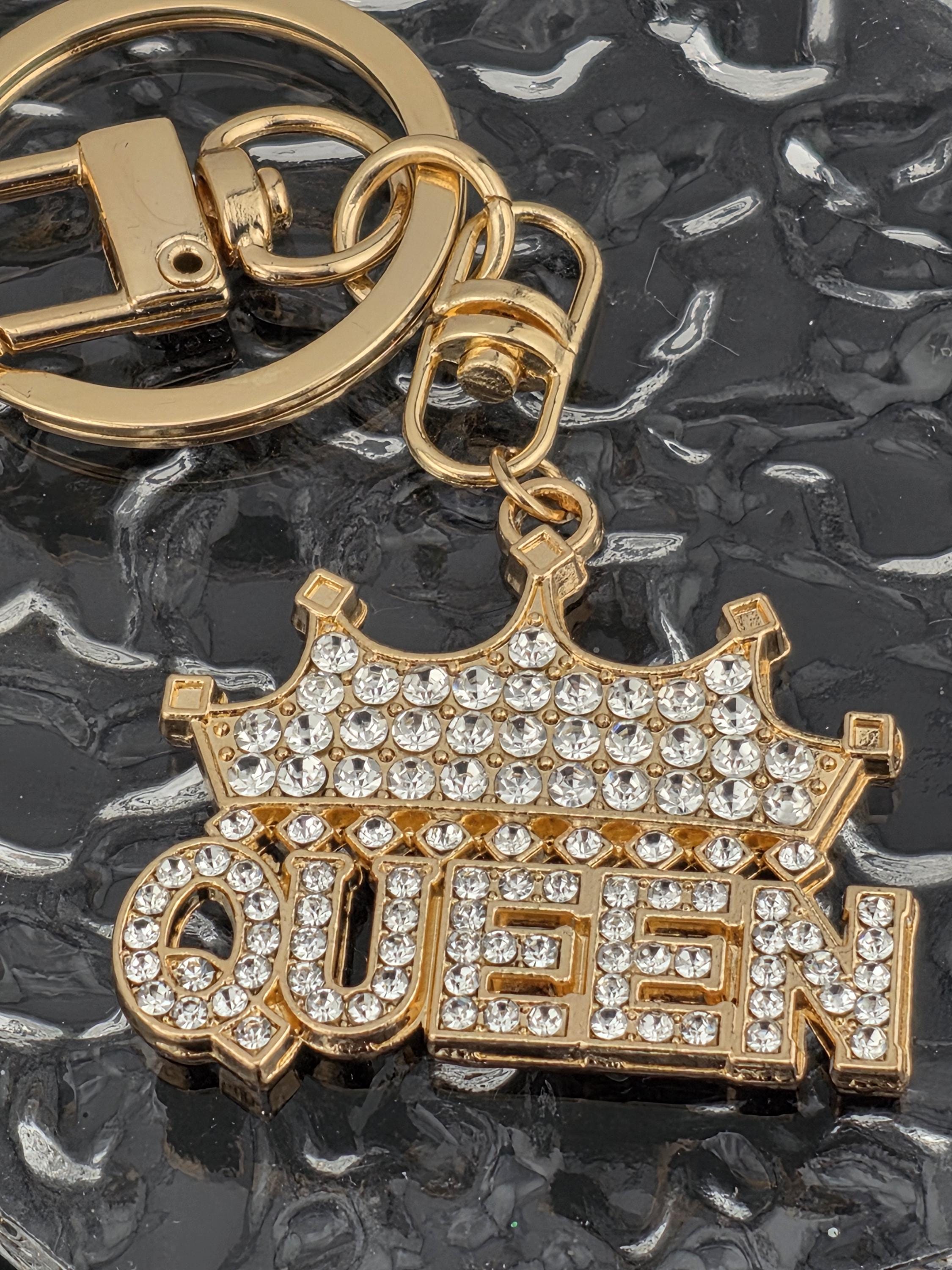 A gold-colored keychain with a large, sparkling crystal-encrusted letter "Q" attached to it.