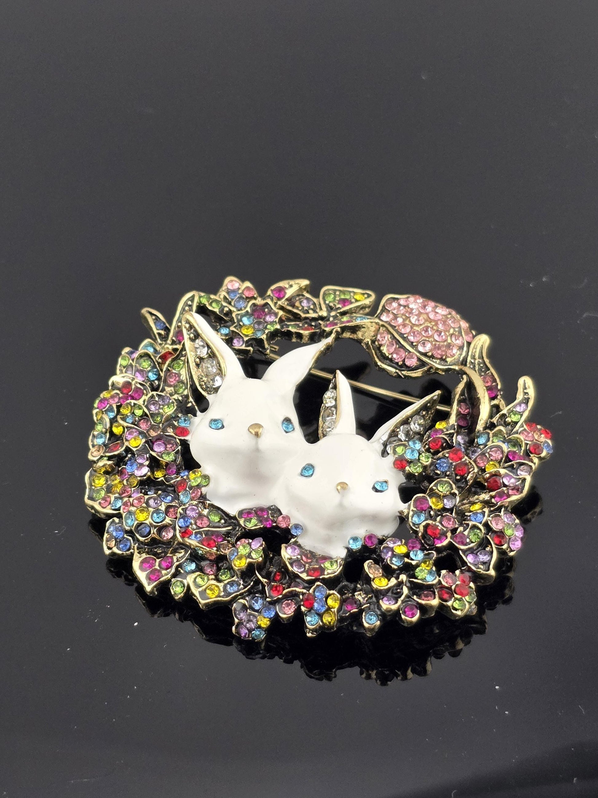 A decorative brooch with a floral design and colorful gemstones.