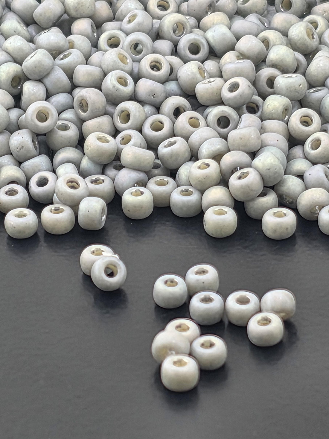 a large pile of small, white beads scattered on a dark surface.