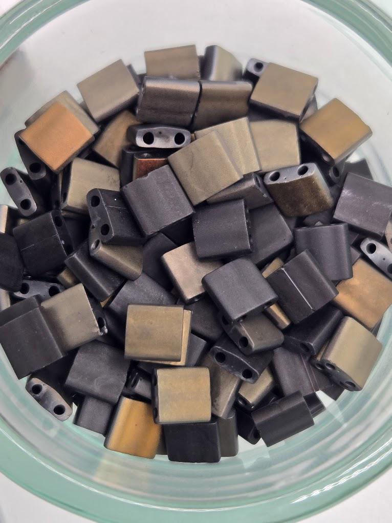 A glass bowl filled with various metal beads in different shapes and sizes.