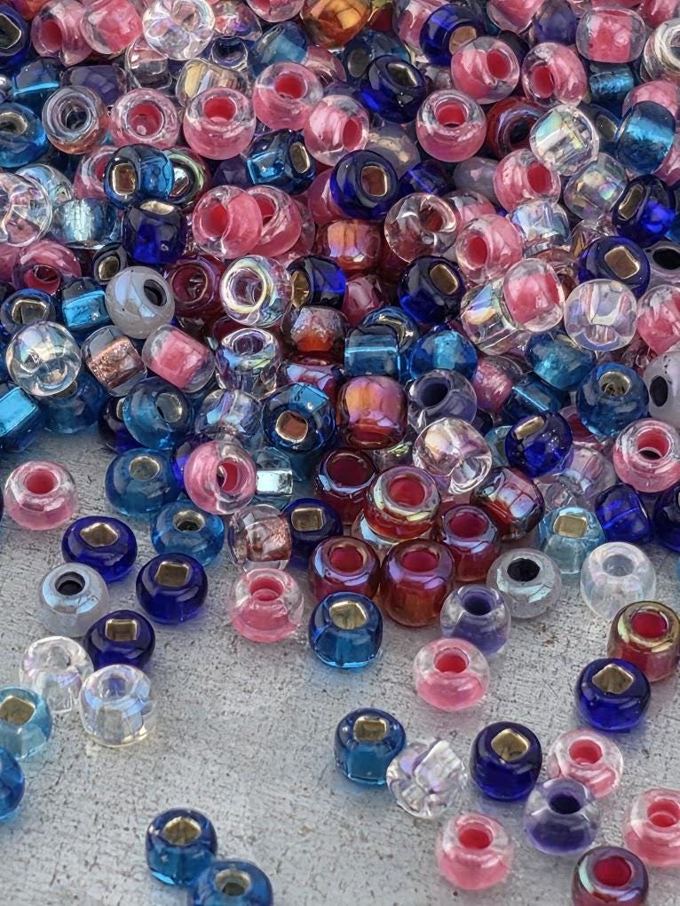 A colorful assortment of glass beads in various colors, including pink, blue, and clear, scattered across a surface.