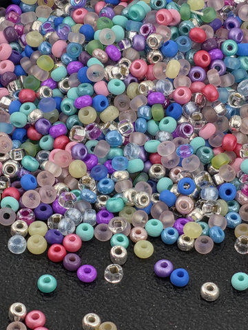 A colorful assortment of multicolored beads, including clear, transparent, and colored glass beads, scattered on a dark surface.