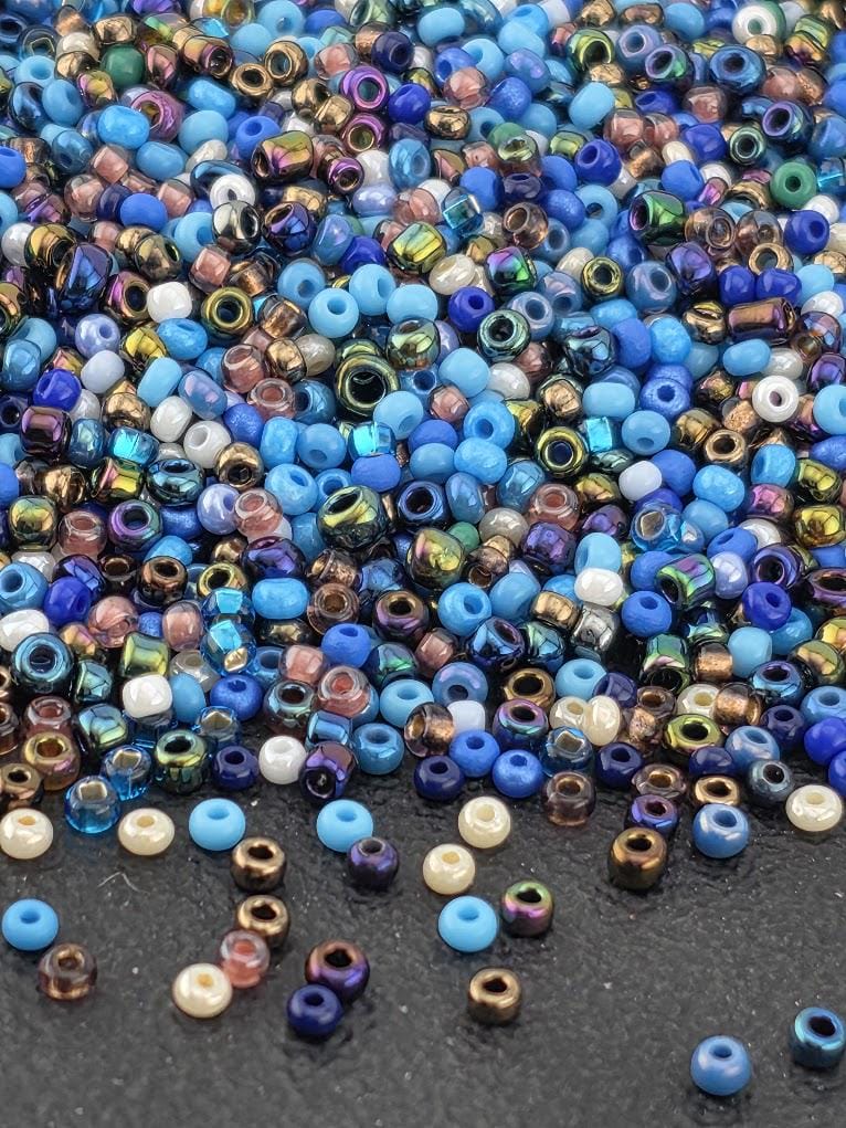 A colorful assortment of multicolored beads, including blue, green, purple, and gold, scattered across a dark surface.