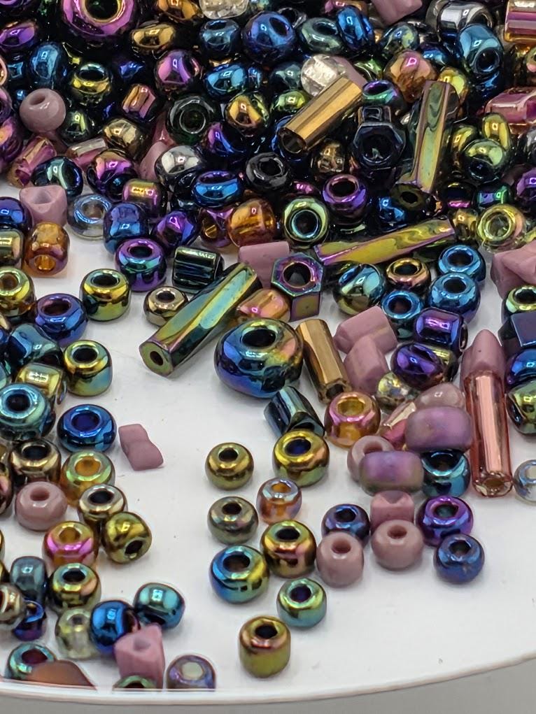 A colorful assortment of multicolored beads, including metallic and glass beads, scattered on a surface.