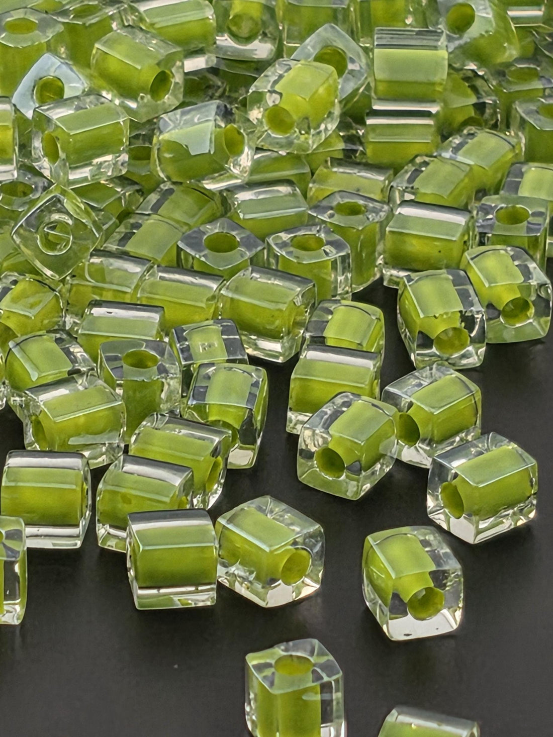 numerous transparent, hexagonal-shaped objects with a vibrant green color, scattered across a dark background.