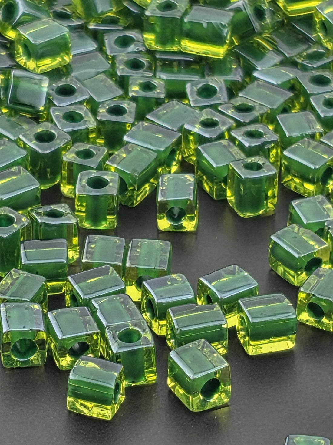a collection of green glass beads scattered on a surface, with some of the beads overlapping each other.