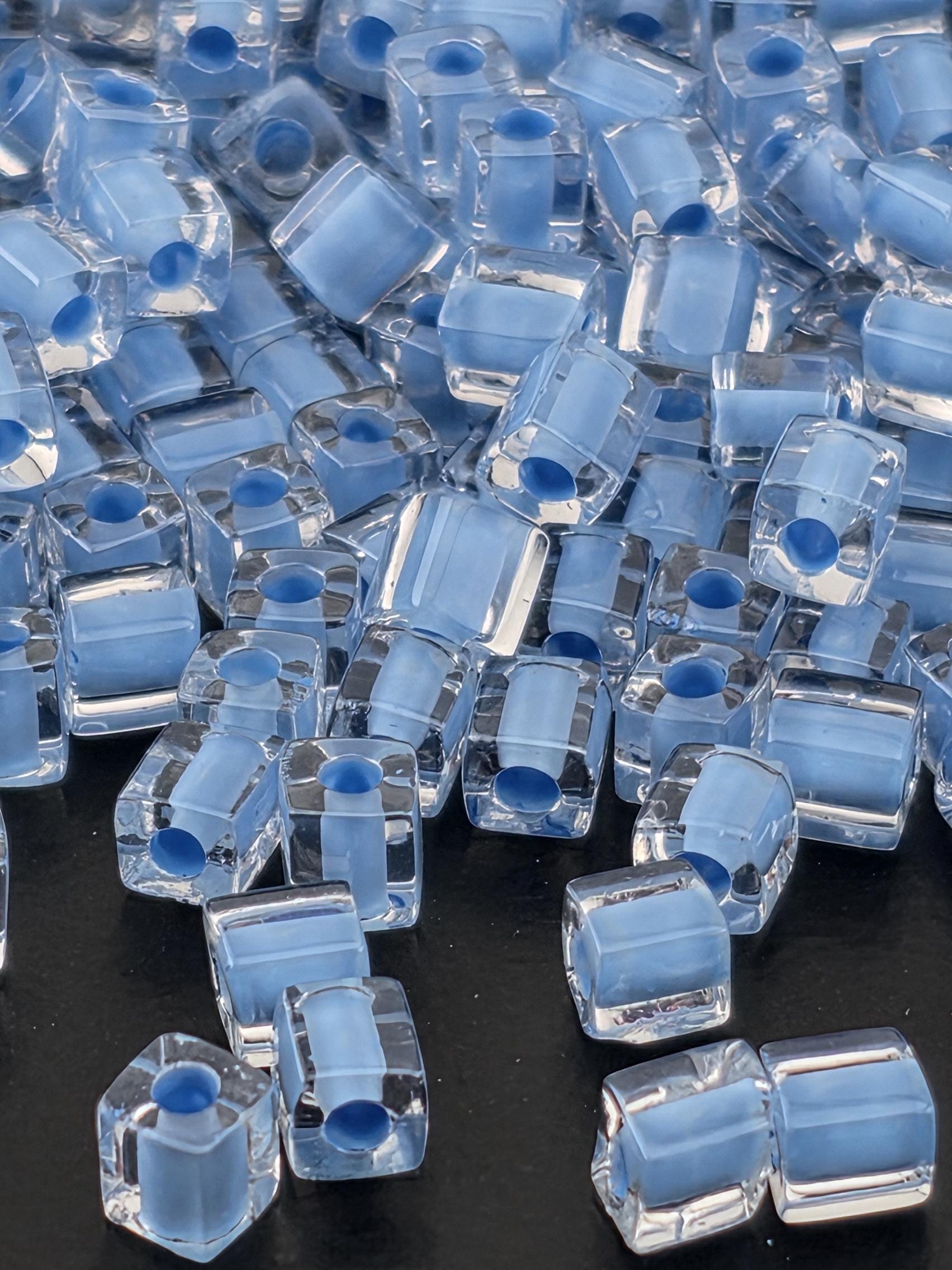 numerous clear glass beads with blue accents, scattered across a dark background.