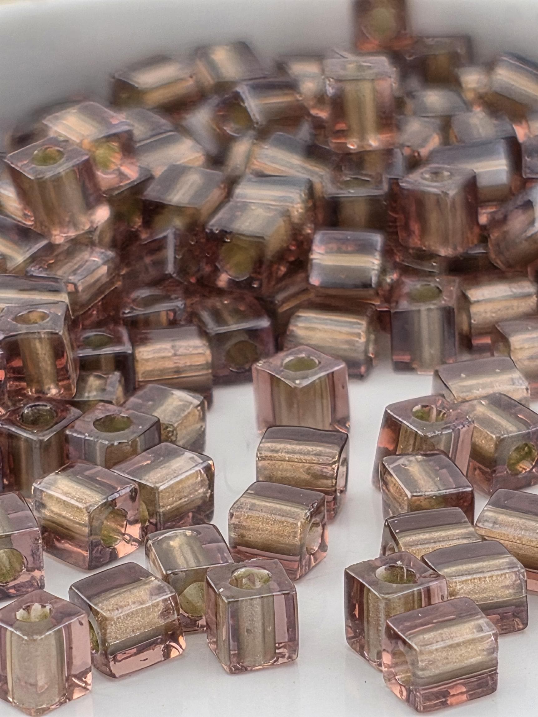 a close-up view of numerous small, clear beads in various shades of brown and beige, scattered across a surface.