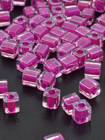 numerous small, clear, and transparent beads in a vibrant shade of pink, scattered across a dark background.