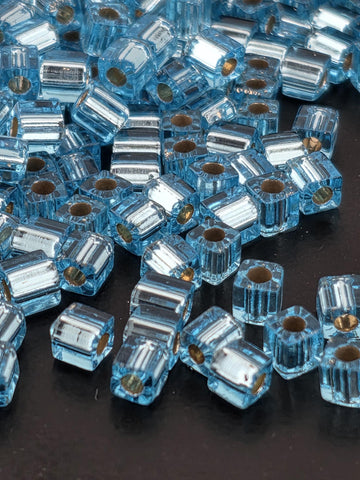 a close-up view of numerous small, clear glass beads scattered on a dark surface.