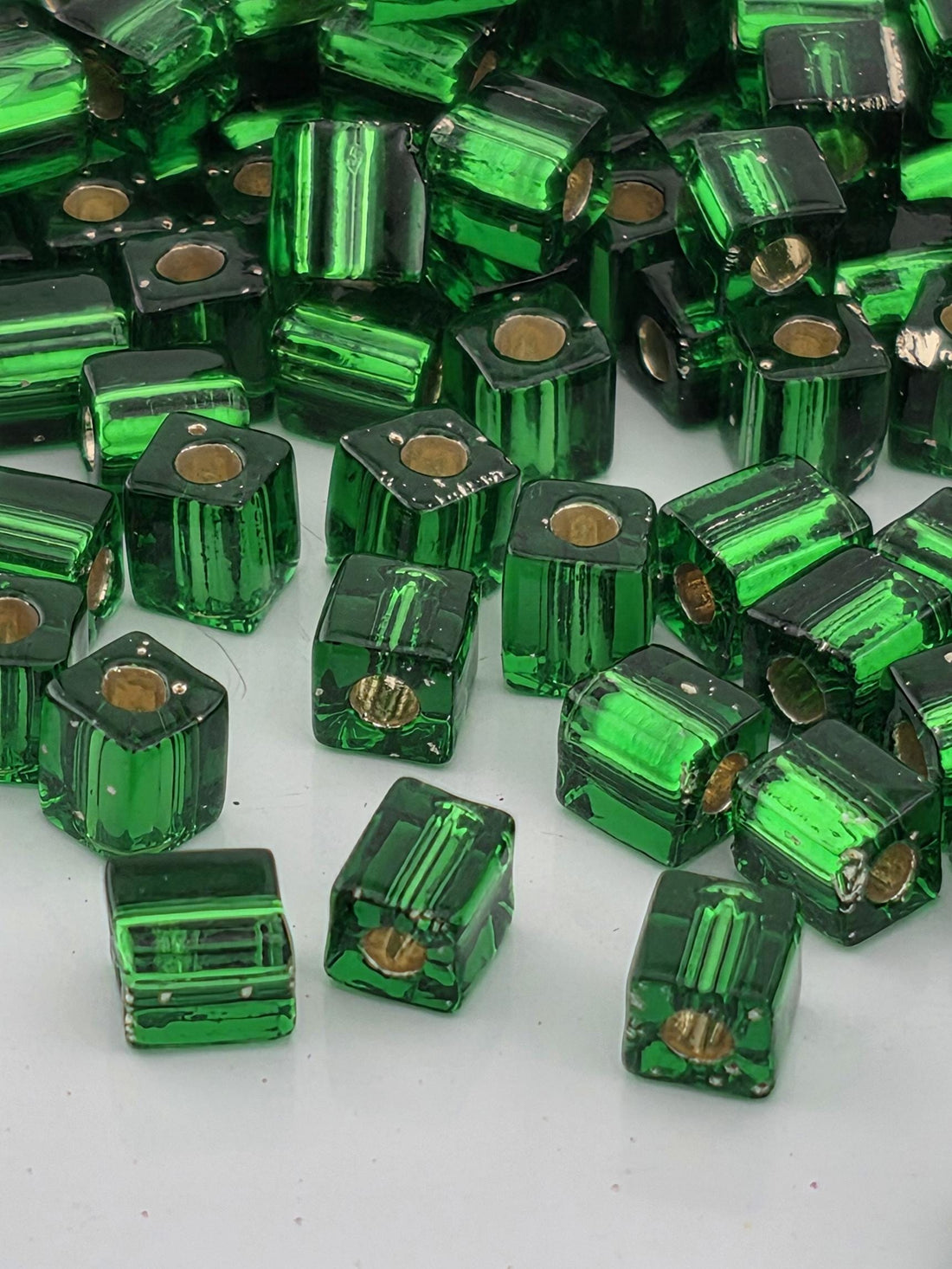 a collection of green glass beads scattered on a white surface.