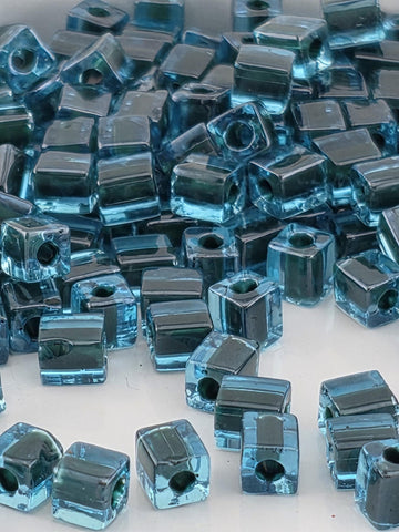 numerous small, clear blue glass beads scattered across a surface.