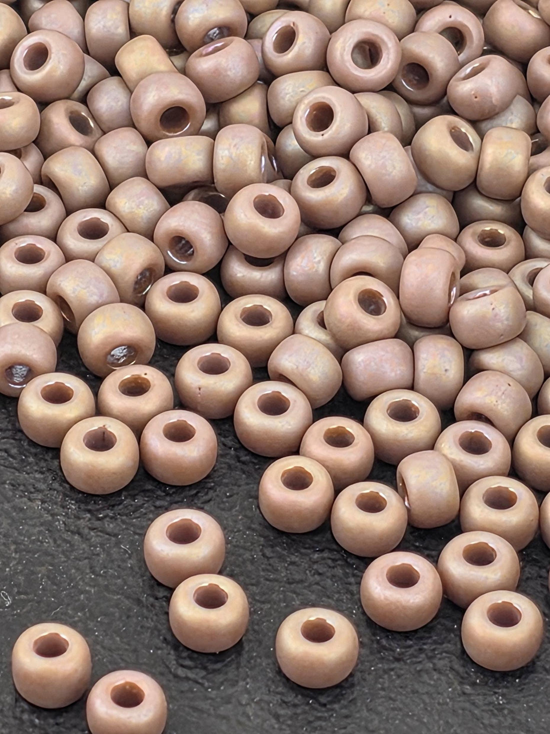 a large pile of small, round beads scattered on a dark surface.