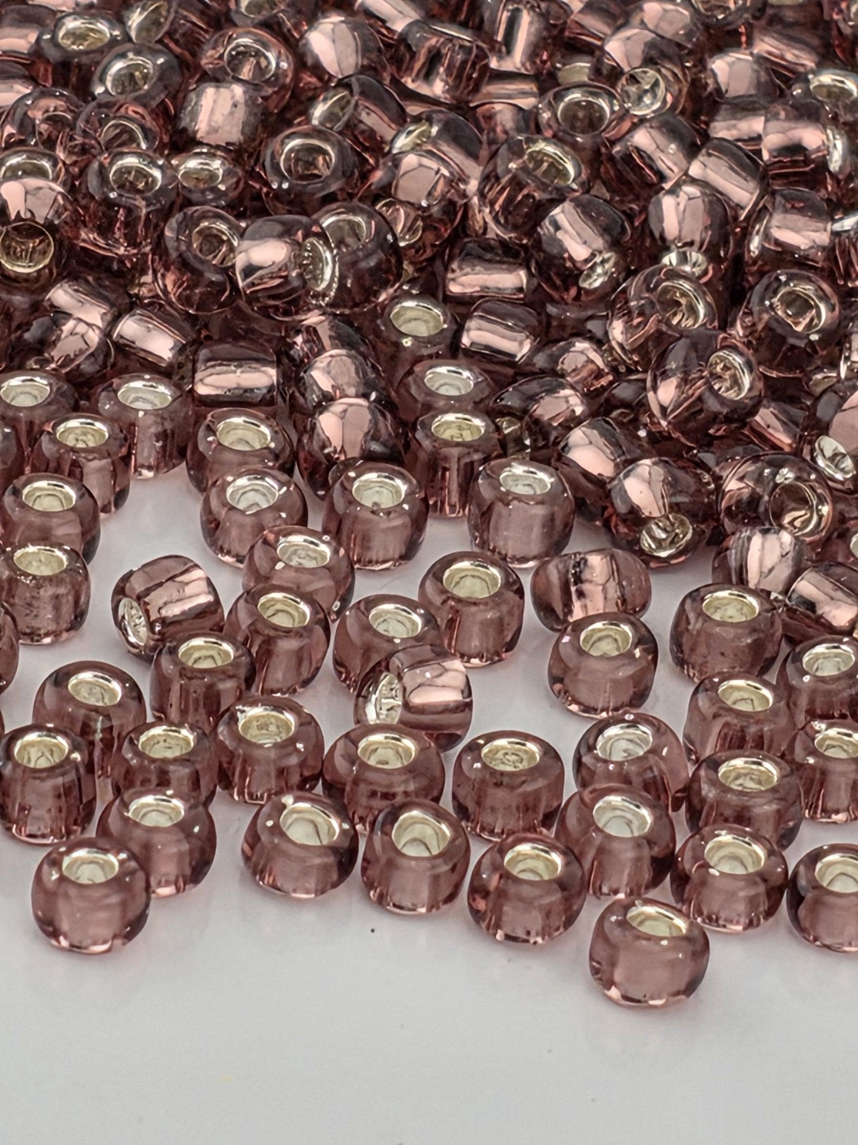 a close-up view of numerous small, clear beads in shades of pink and purple, scattered across a surface.