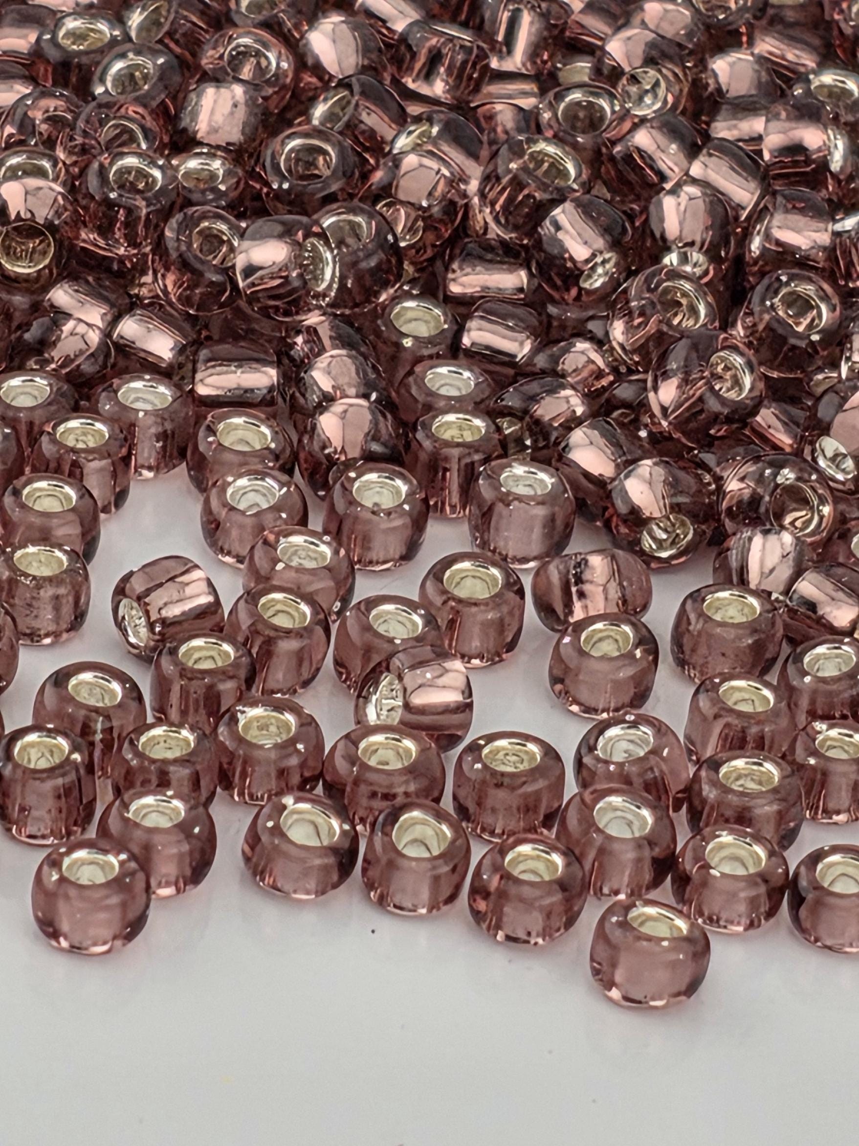 a close-up view of numerous small, clear beads in shades of pink and purple, scattered across a surface.