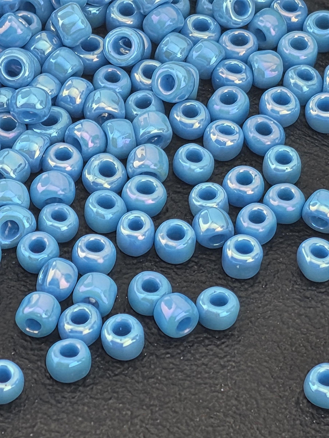 a collection of small, round blue beads scattered on a dark surface.