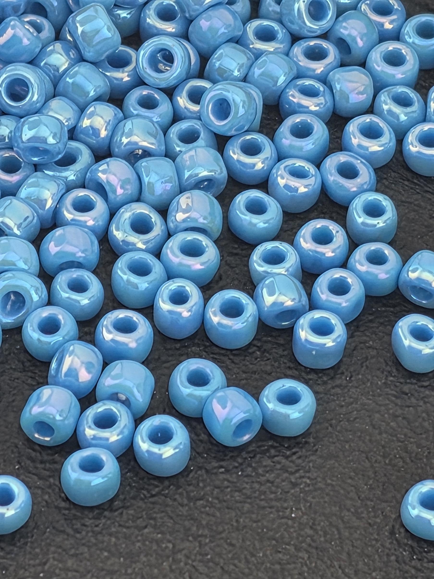 a collection of small, round blue beads scattered on a dark surface.